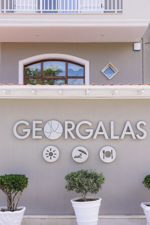 A building with the name 'GEORGALAS' prominently displayed on the facade, accompanied by symbols representing sun, relaxation, and dining. - Georgalas Sun Beach Resort (Nea Propontida)