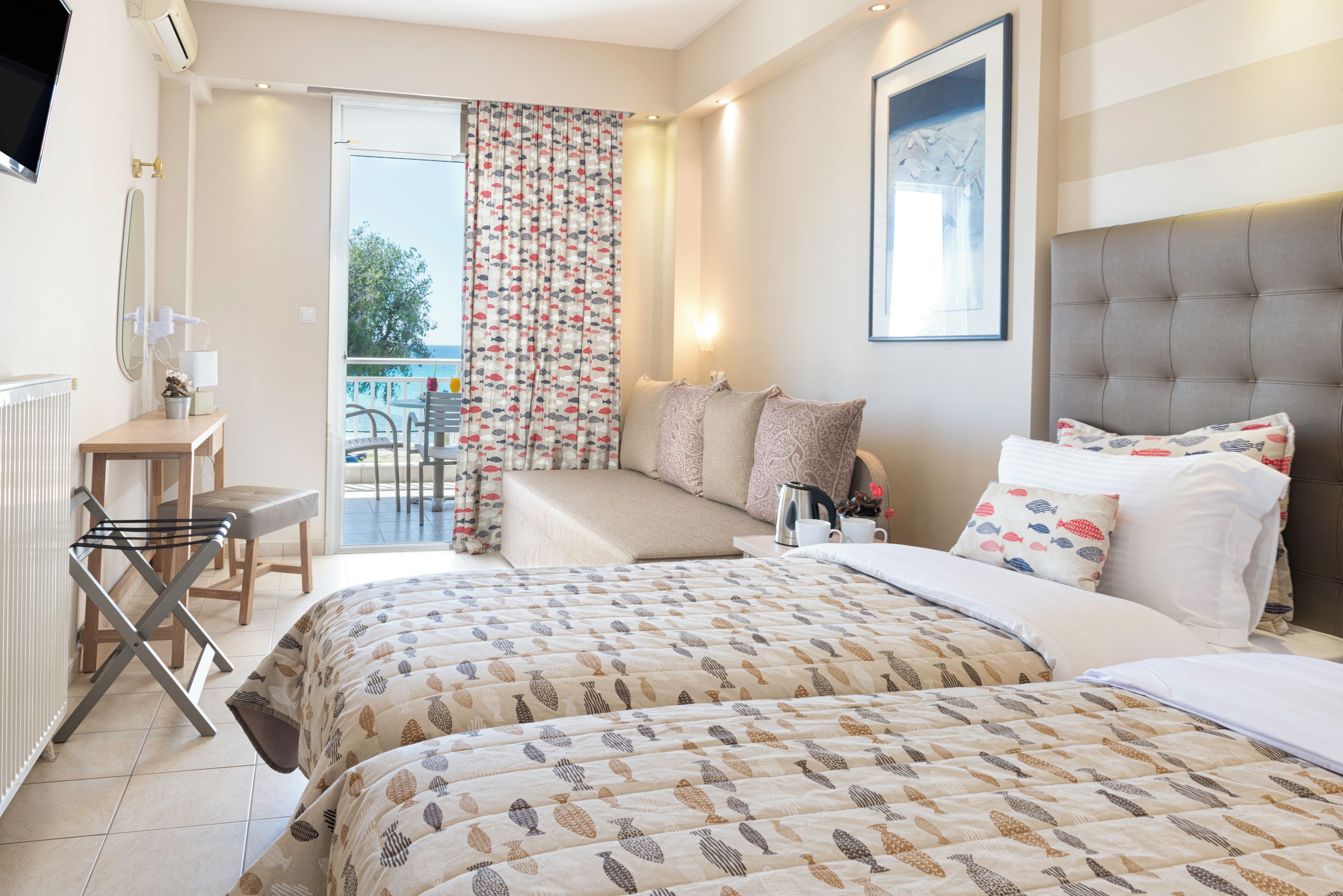Habitación de hotel con cama, escritorio, silla, mesa y vista al mar a través del ventanal.