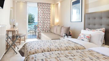 Habitación de hotel con cama, escritorio, silla, mesa y vista al mar a través del ventanal.