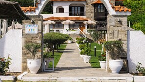 Uma villa de praia na Geórgia, com fachada de pedra, telhado em terracota e um arco central que dá acesso à entrada.