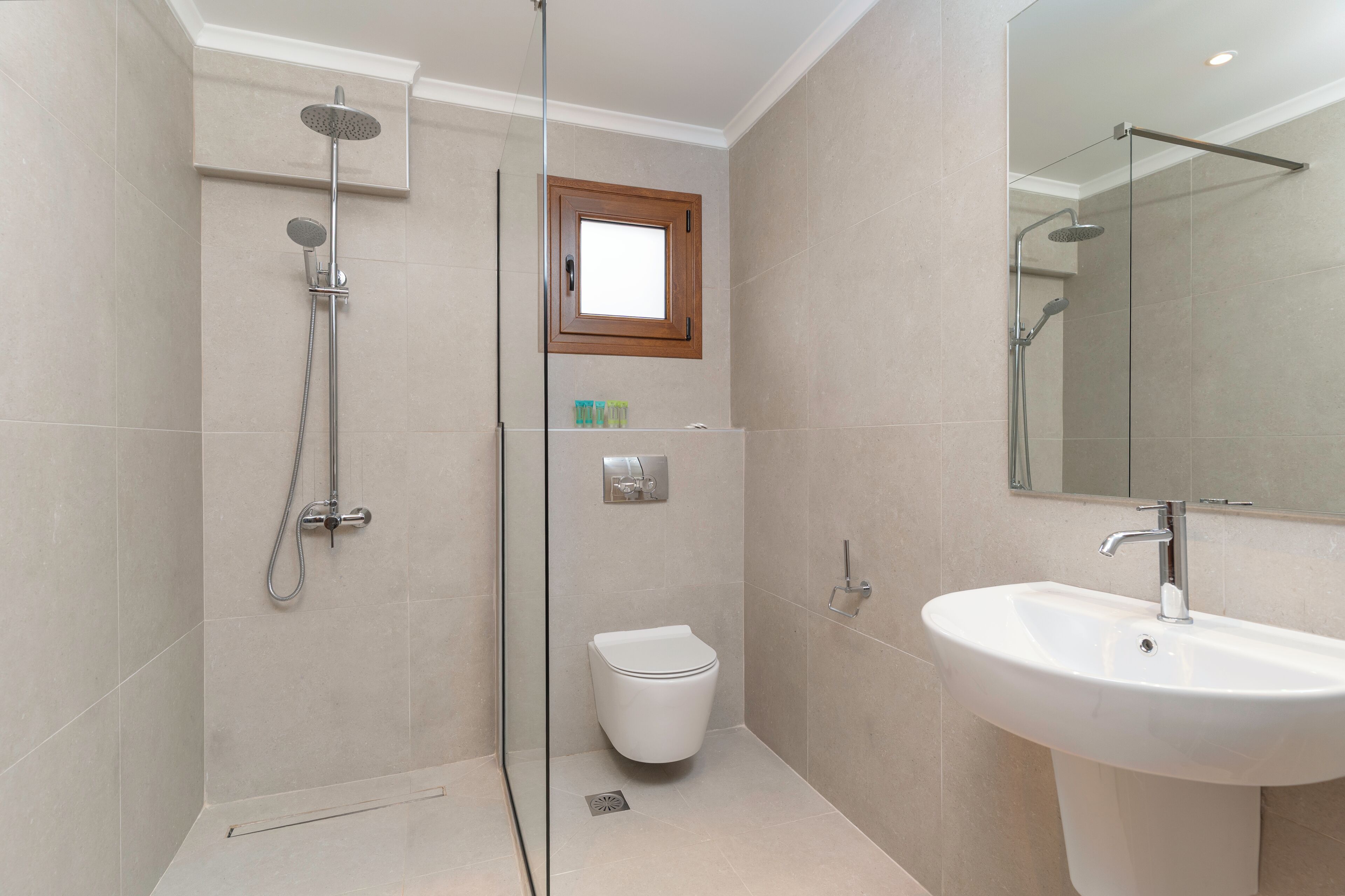 Un baño moderno con ducha de vidrio, inodoro blanco y lavabo con espejo.