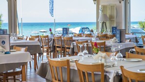 Um restaurante com mesas preparadas para refeições, com vista para o mar.