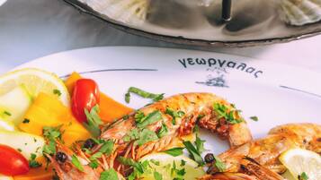 Un plato de mariscos con camarones, limón y verduras.