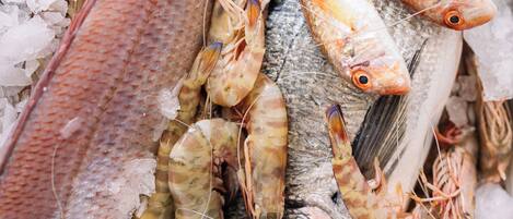 Eine Auswahl an Meeresfrüchten, darunter Fisch und Garnelen, auf Eis präsentiert.