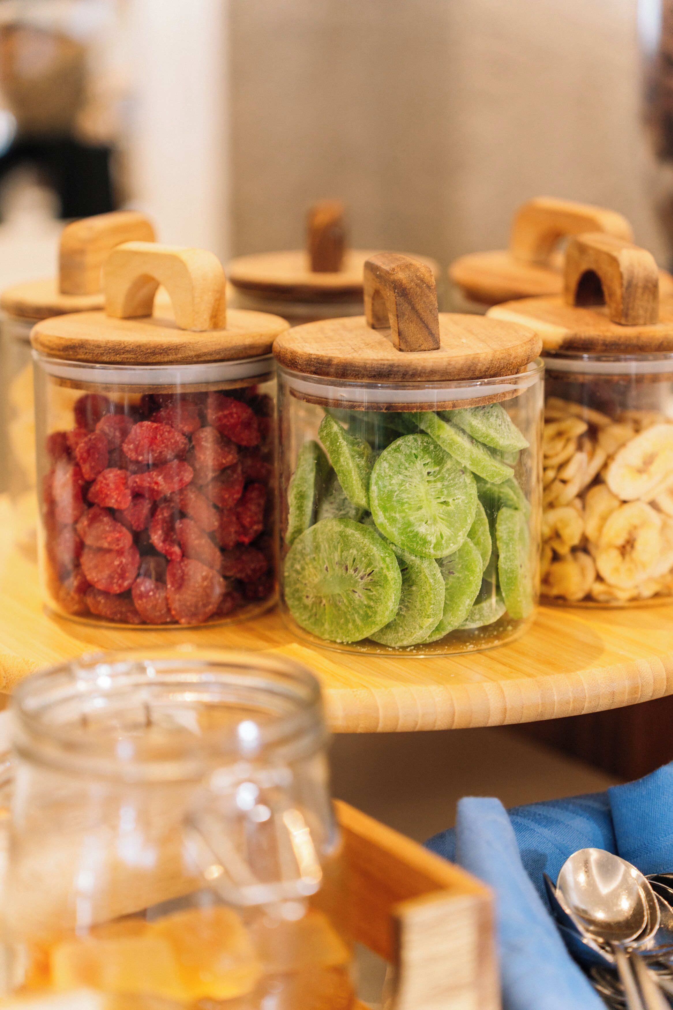 Una mesa de madera con frascos de vidrio llenos de frutas secas y nueces.