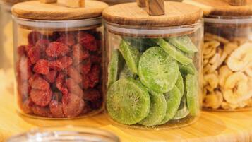 Una mesa de madera con frascos de vidrio llenos de frutas secas y nueces.