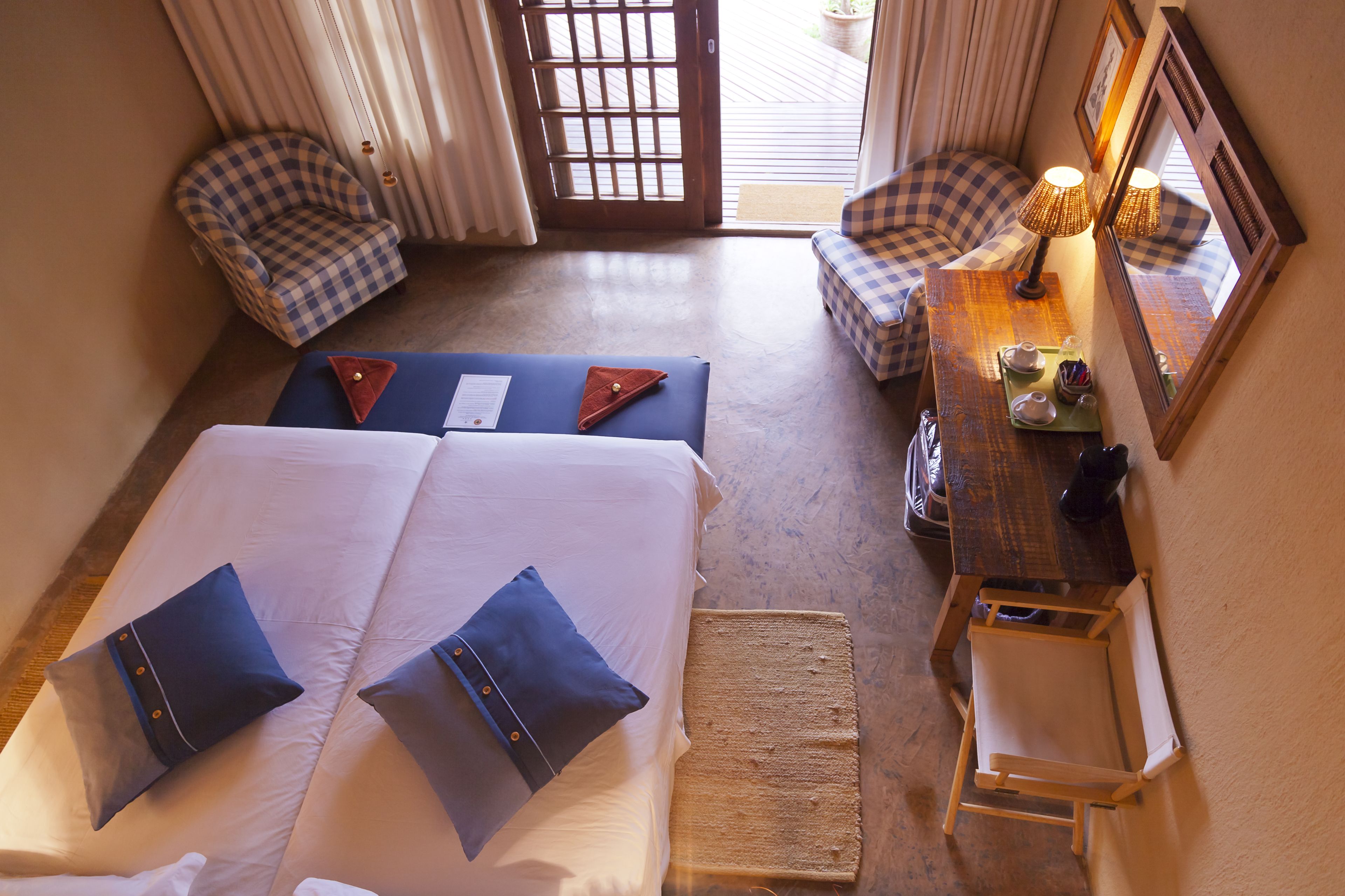 A hotel room with a large bed, two bedside tables, a chair, and a small desk with a lamp.