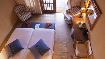 A hotel room with a large bed, two bedside tables, a chair, and a small desk with a lamp.
