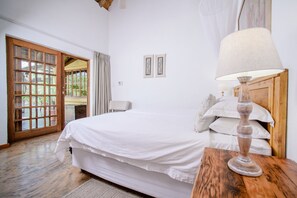 Relax in this serene bedroom with a large bed, nightstand, and sliding door leading to an outdoor area.
