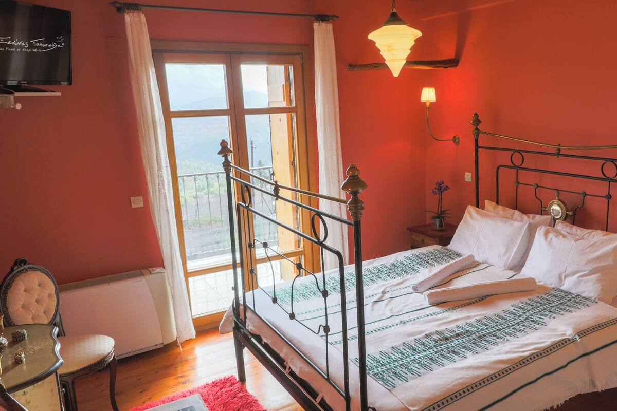 Ein Schlafzimmer mit Bett, Stuhl, Nachttisch, Lampe und einem Fenster mit Blick.