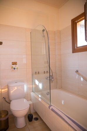 Un baño moderno con ducha de mampara de vidrio, inodoro blanco y bañera.