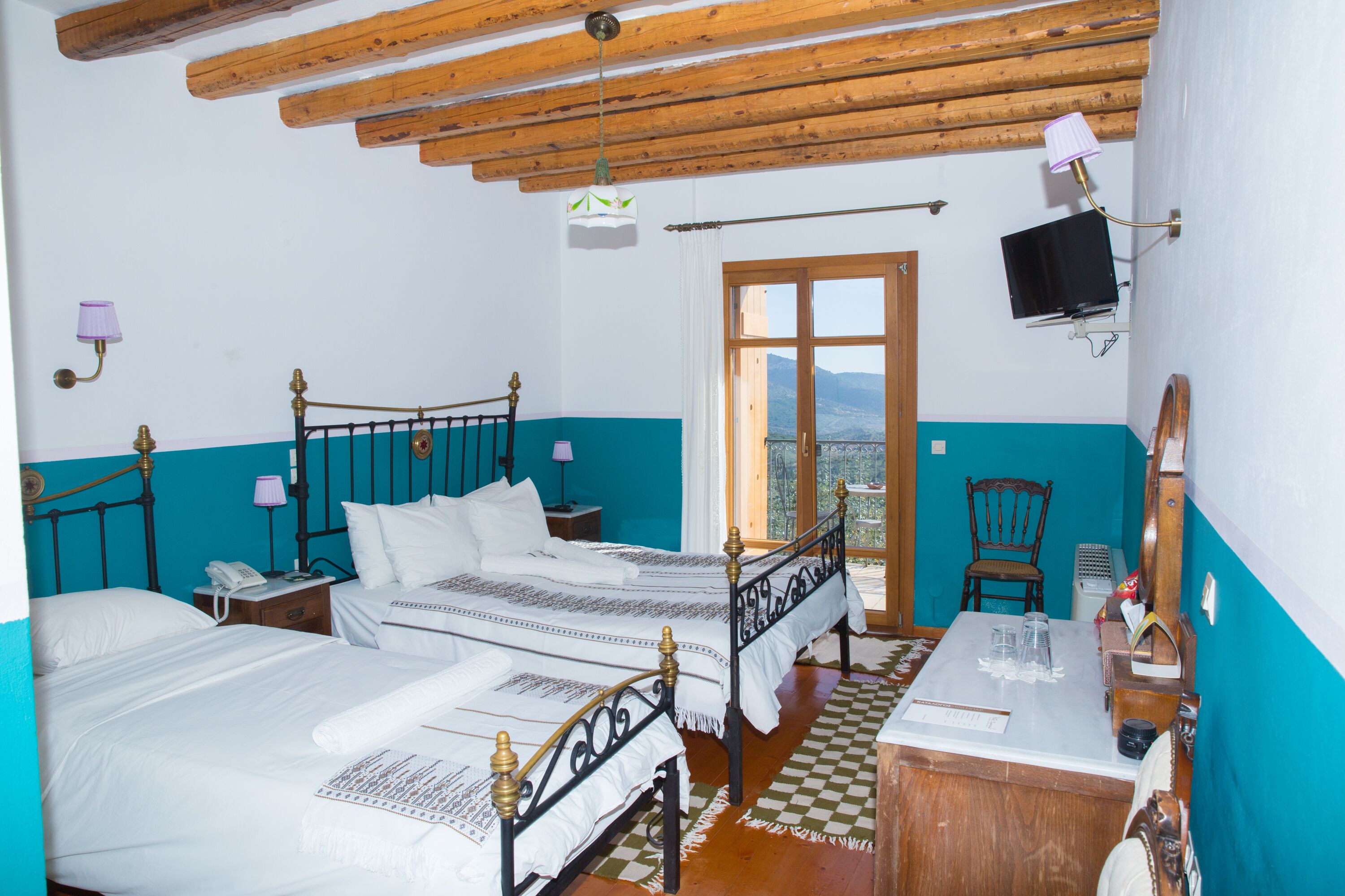 A bedroom with two beds, a wooden ceiling, a television, and a view of the outdoors.