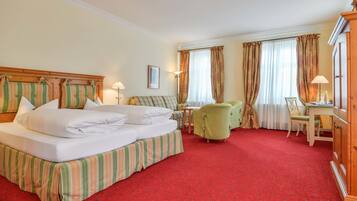 Una habitación de hotel con una cama grande, dos sillas, un escritorio y un armario.