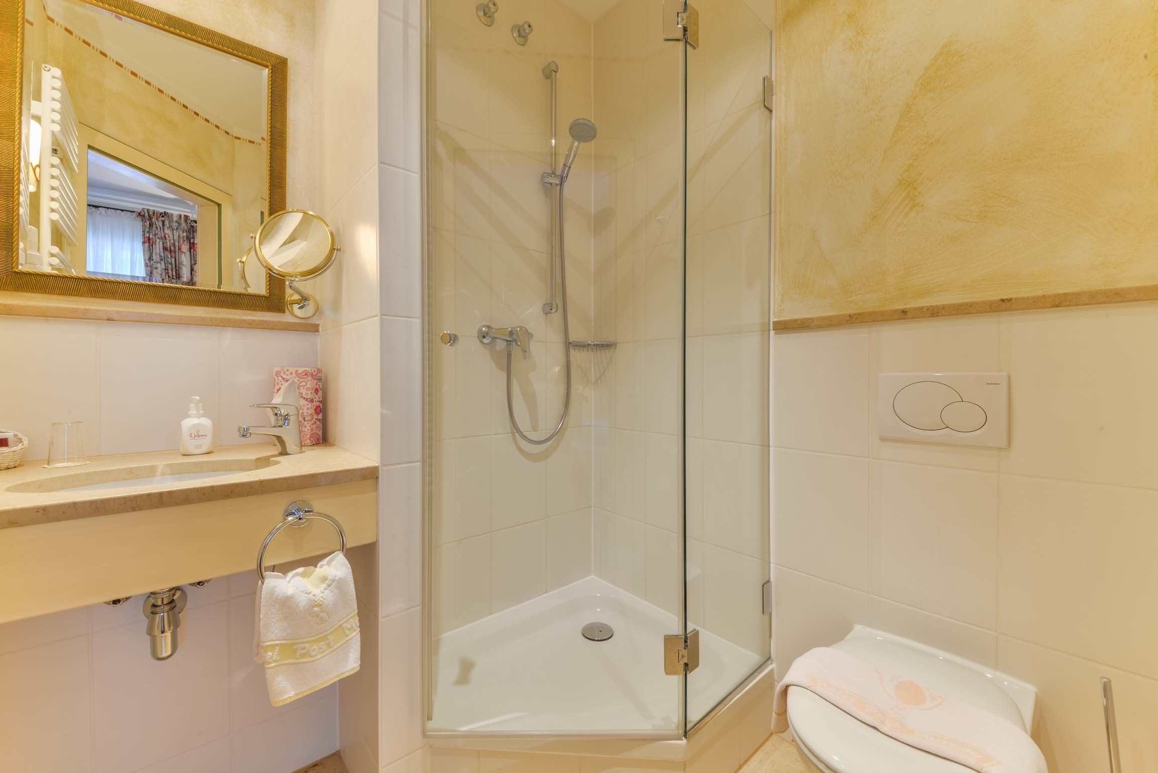 Une salle de bain avec une douche à parois de verre, un lavabo avec un miroir et des toilettes.
