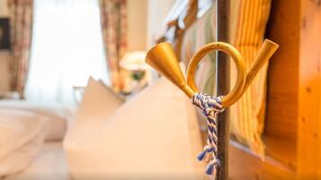 A room with a bed, a wooden post with a rope tied around it, and a window with curtains.