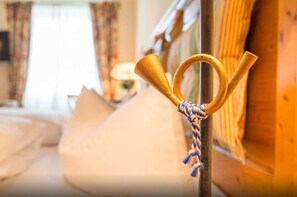 A room with a bed, a wooden post with a rope tied around it, and a window with curtains.
