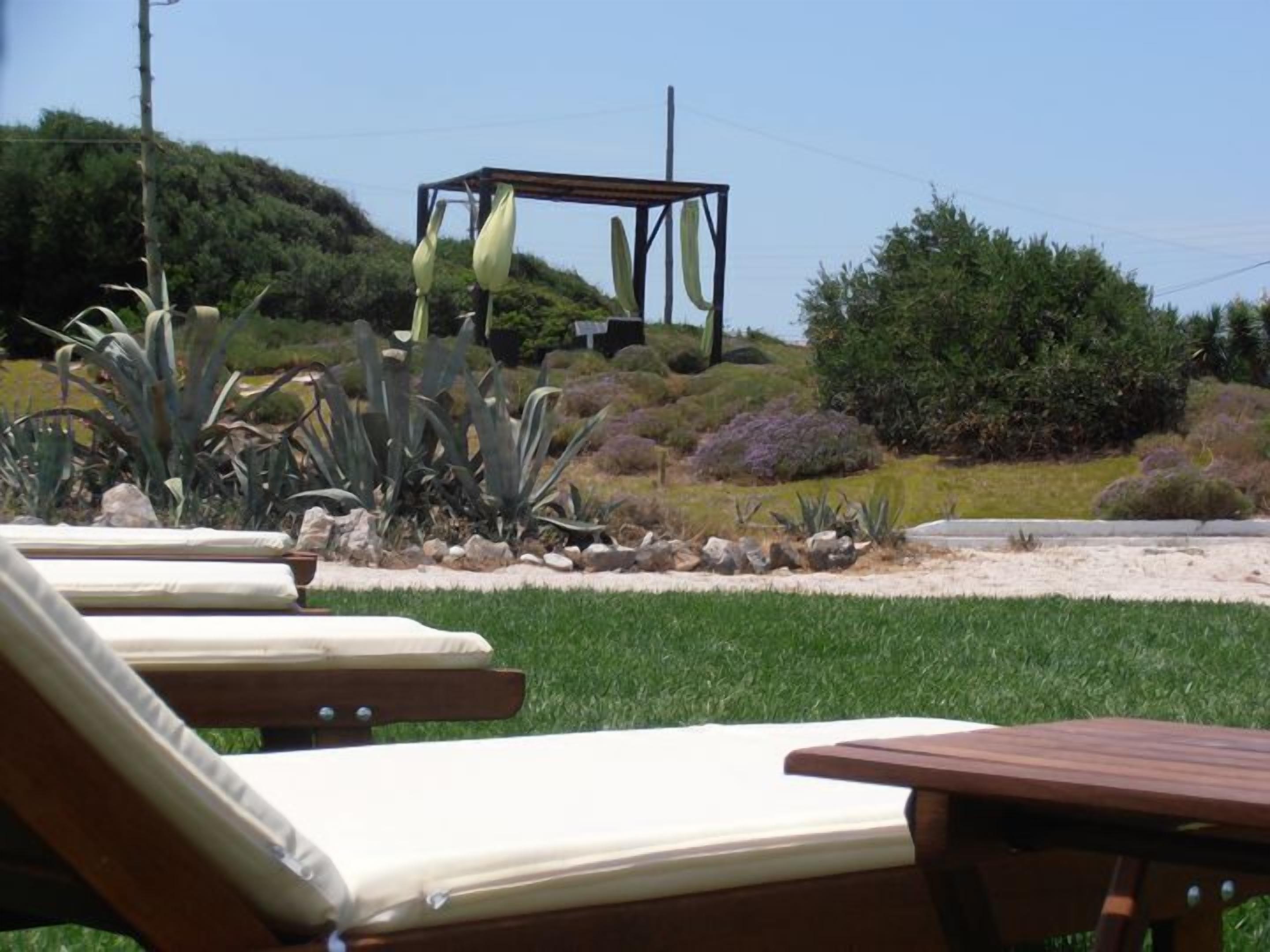 Ein Garten mit einem Holztisch und Liegestühlen.