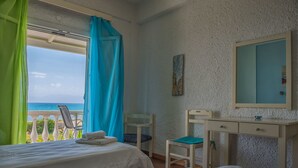 Un dormitorio con cama, una silla, un escritorio y una ventana con cortinas.