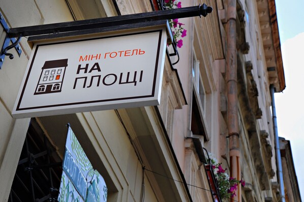A hotel sign with a building icon and text in Cyrillic script. - On The Square  (Lviv)