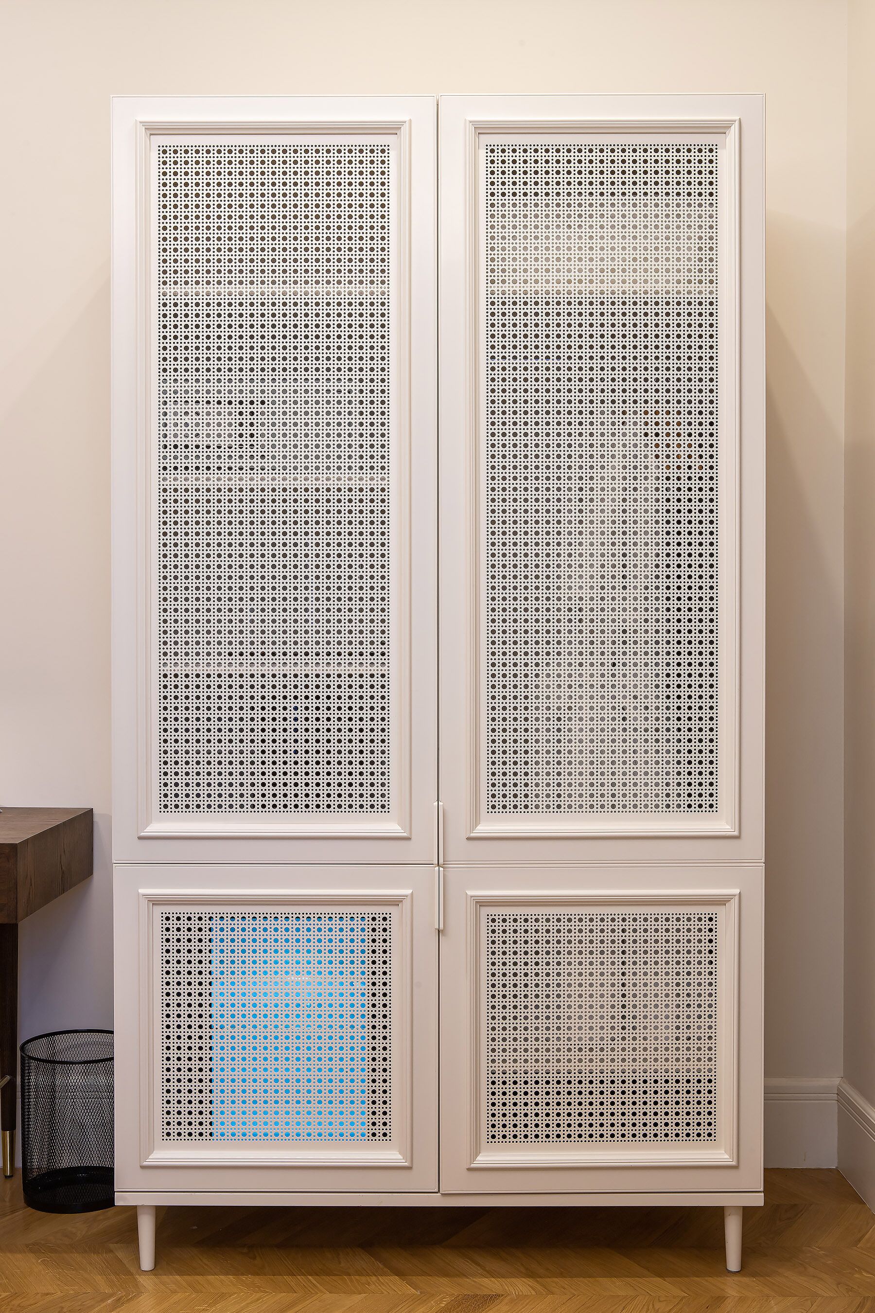 Un mueble blanco con cuatro cajones, cada uno con un frente perforado.