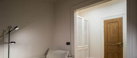 A cozy room with a sofa, a lamp, a chair, and a wooden door.