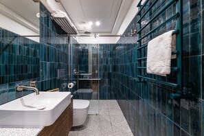 A modern bathroom with a white sink, toilet, and shower. - On The Square  (Lviv)