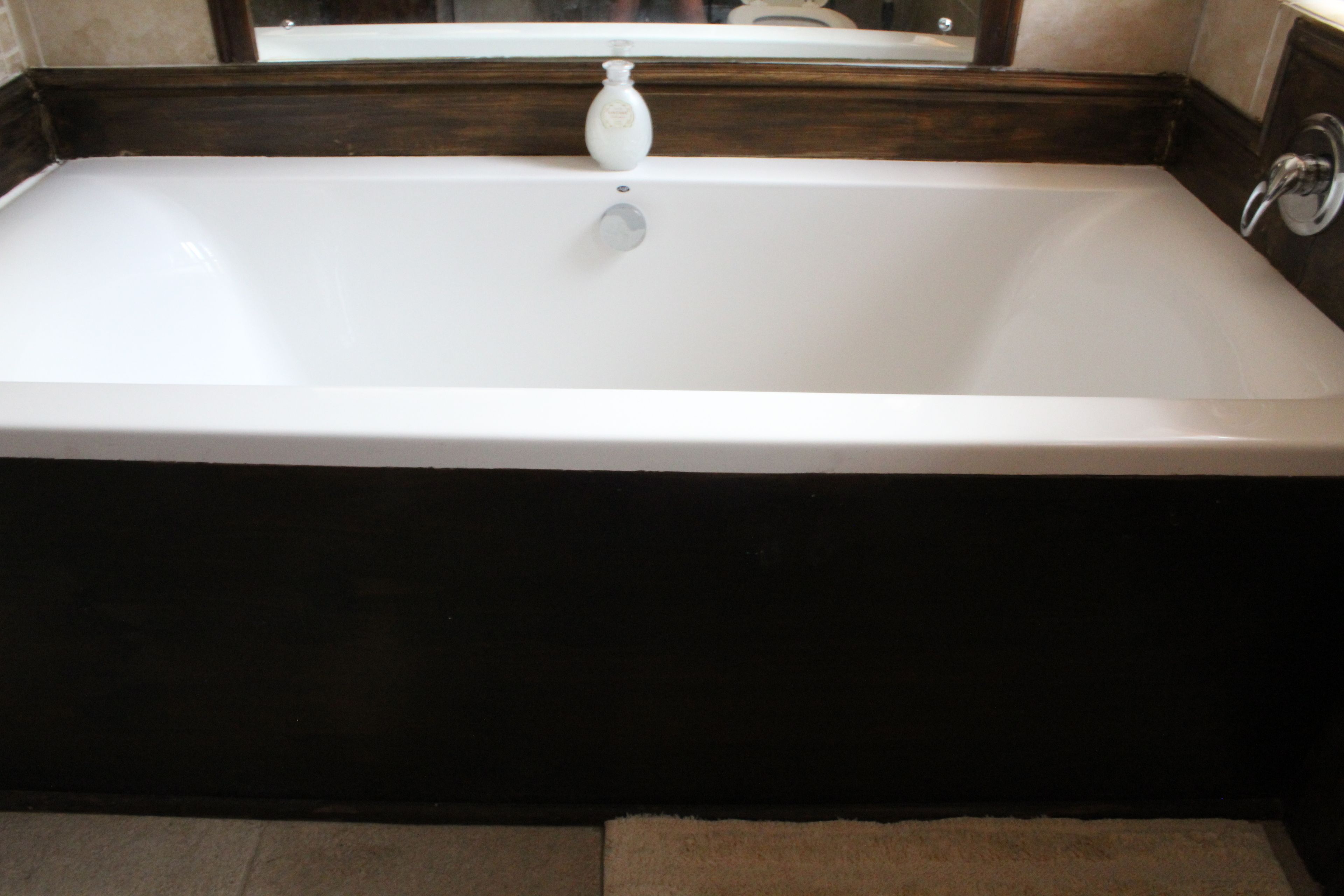 Una bañera rectangular con un grifo y dispensador de jabón.