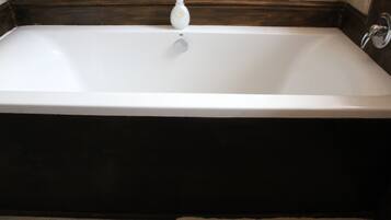 Una bañera rectangular con un grifo y dispensador de jabón.