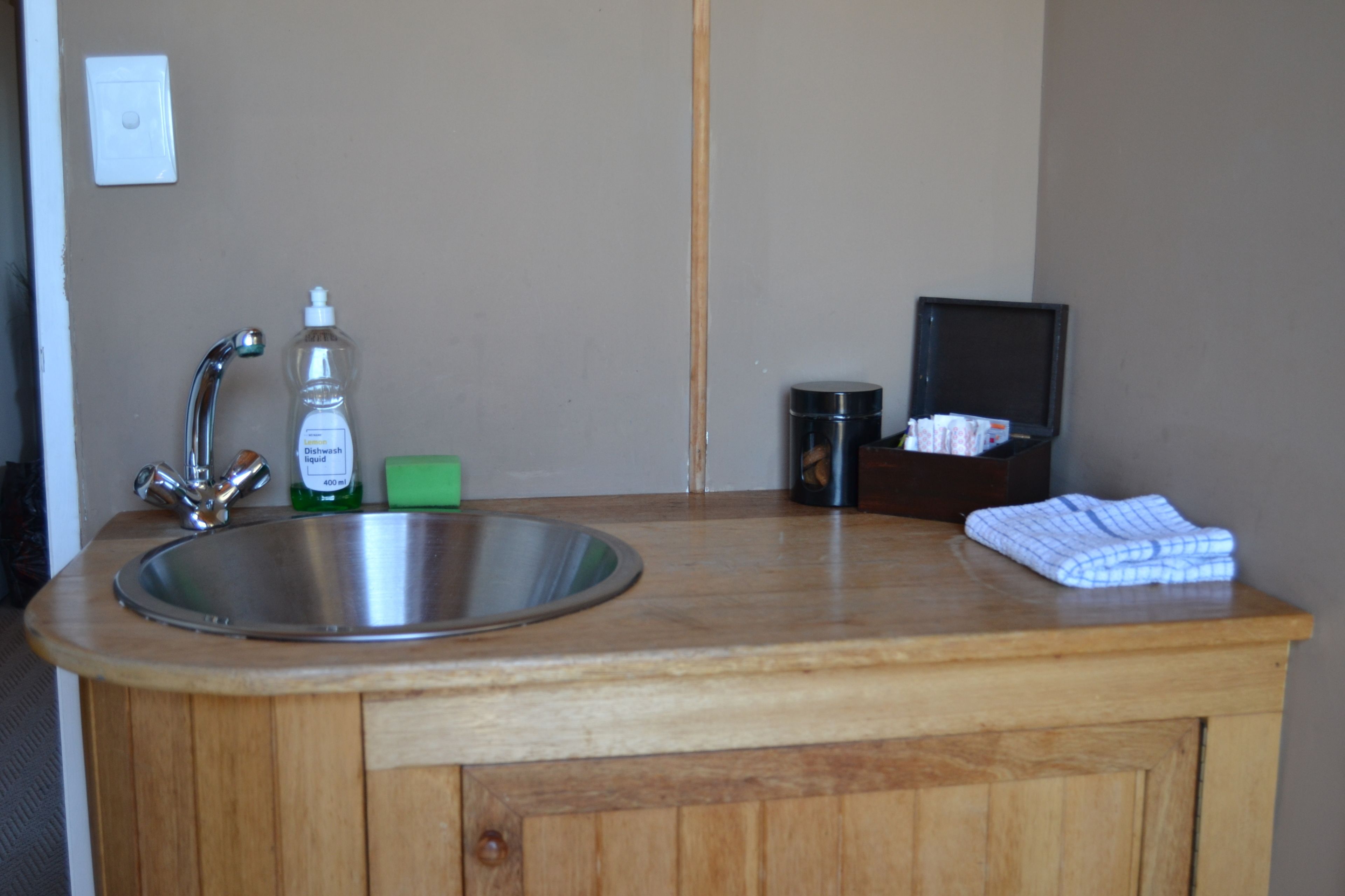 A bathroom with a sink, soap dispenser, and a towel rack.