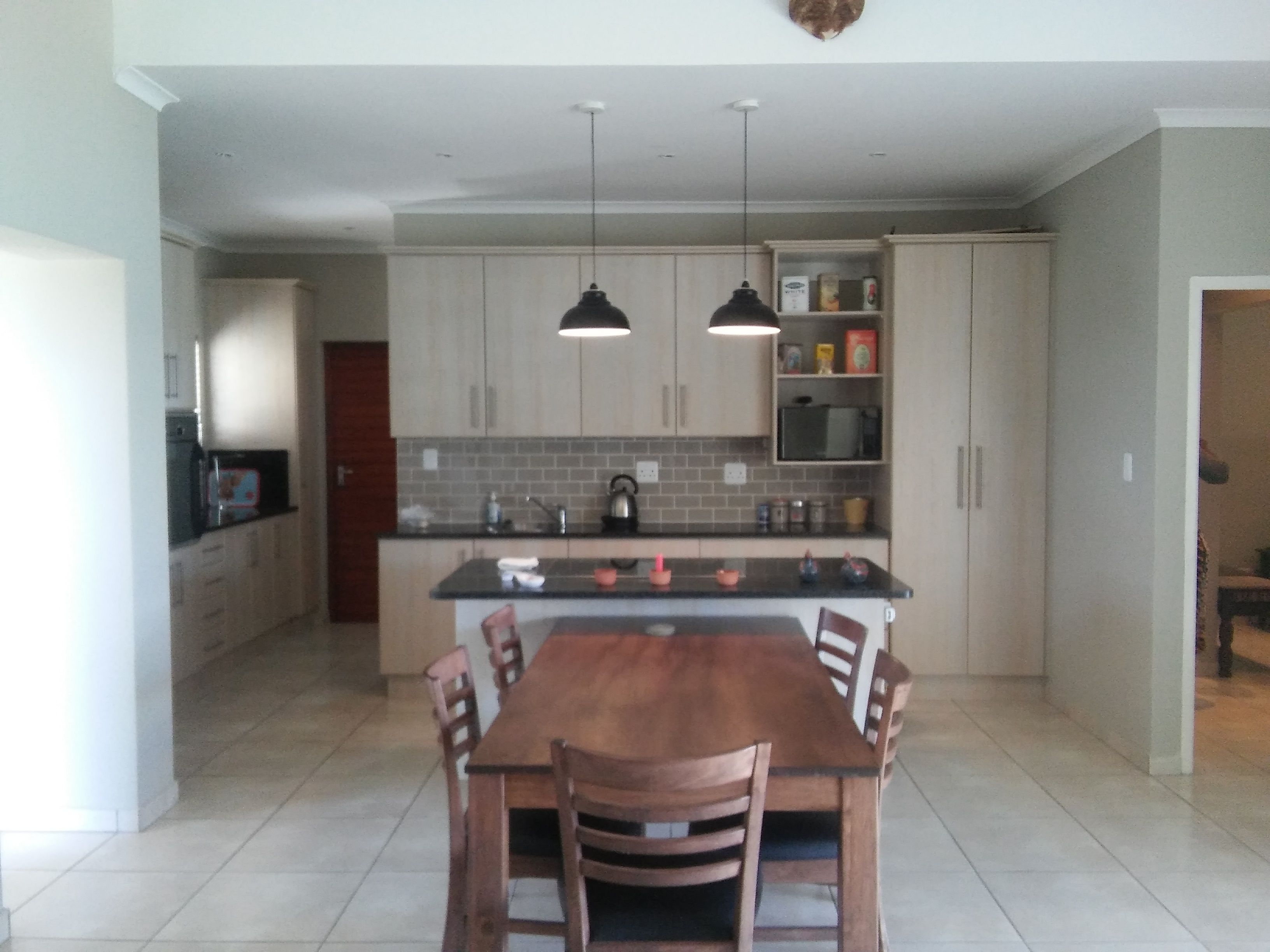Una cocina moderna con una isla central, luces colgantes y muebles empotrados.