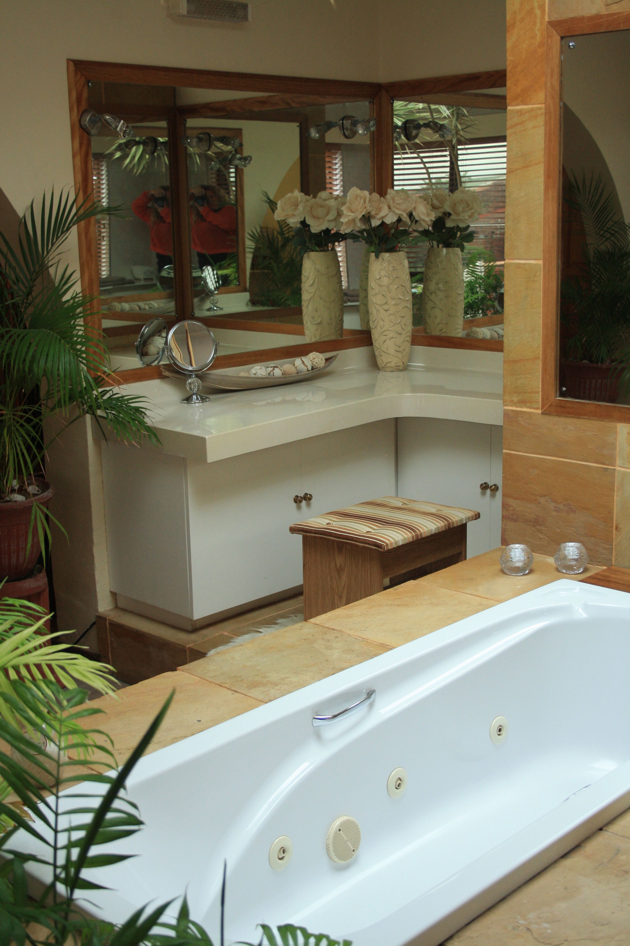 A bathroom with a bathtub, a vanity with a mirror, and a window with a view of the outdoors.