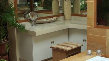 A bathroom with a bathtub, a vanity with a mirror, and a window with a view of the outdoors.