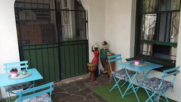 Une terrasse agrémentée de meubles turquoise, d’un tambour et d’une statue.
