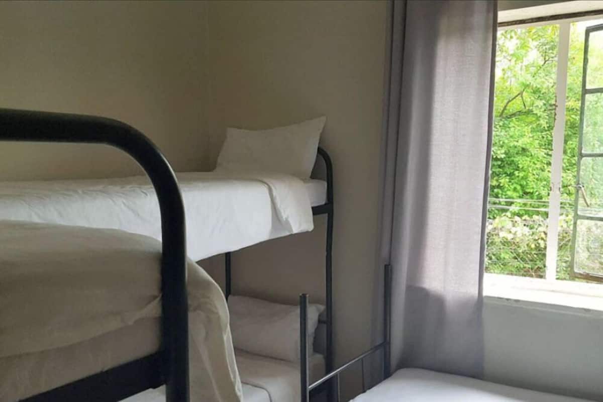 A bunk bed with white bedding in a room with a window and curtains.