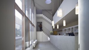 A modern interior with a staircase, a reception desk, and pendant lighting. - Wu Wei (Kortrijk)