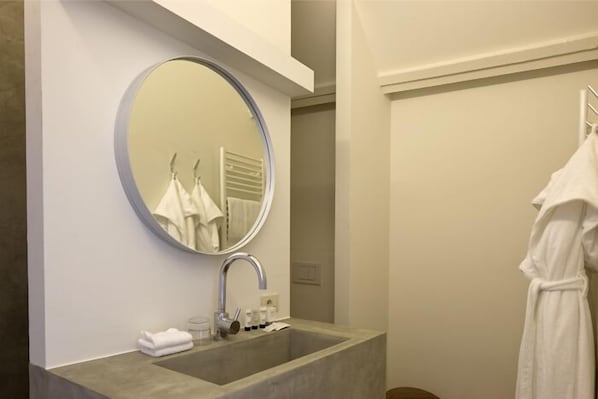 A bathroom with a large mirror, a sink, and a towel rack.