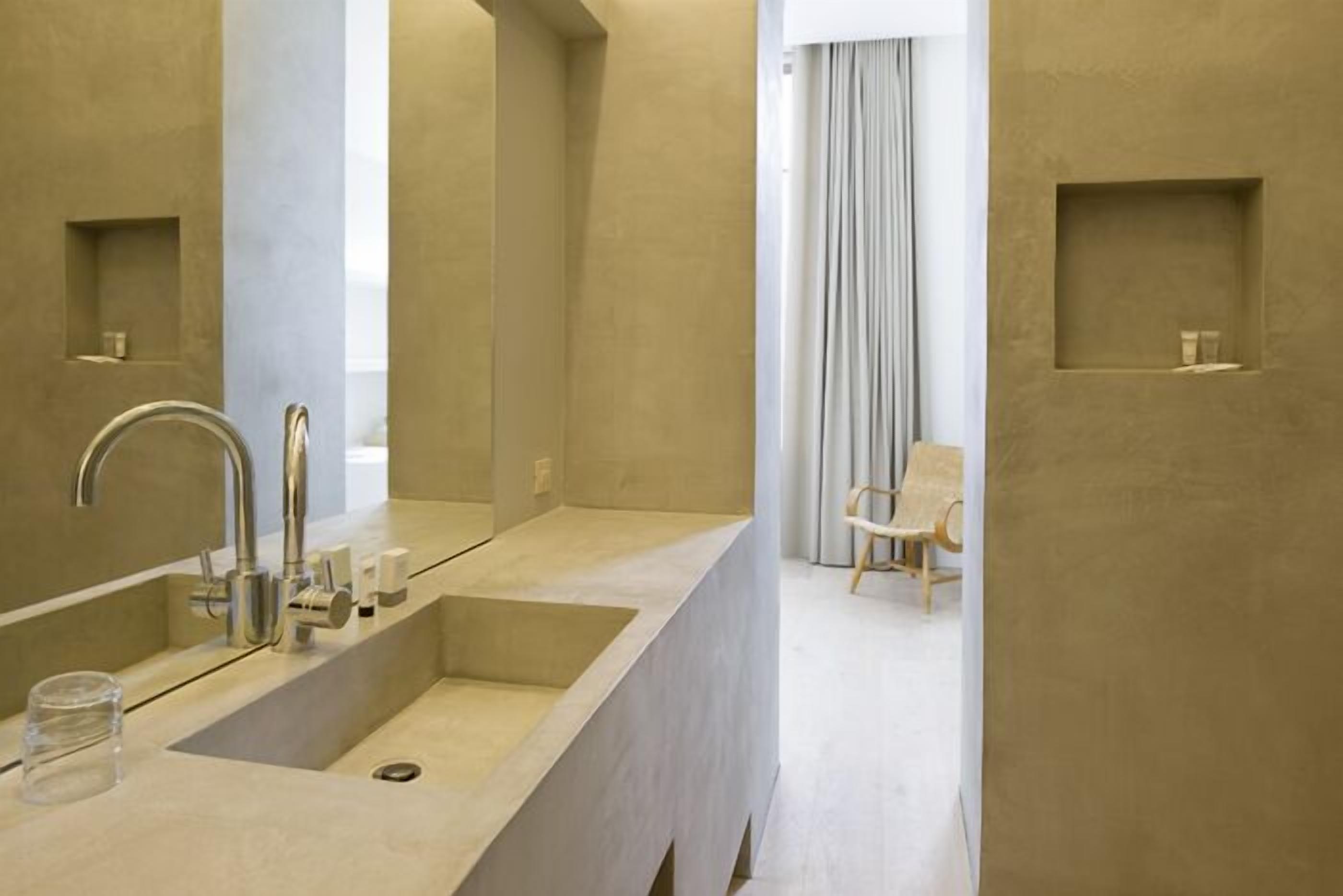 A modern bathroom with a large sink, a mirror, and a shower area.