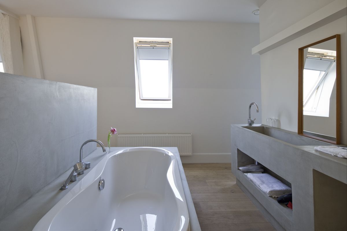 Une salle de bain moderne avec une baignoire sur pieds, un meuble-lavabo avec un miroir et une fenêtre laissant entrer la lumière naturelle.