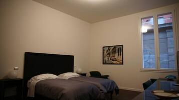 Ein Schlafzimmer mit Bett, Schreibtisch, Stuhl und Fenster.