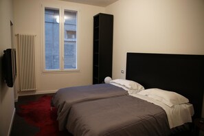 A bedroom with a bed, a radiator, a window, and a black shelving unit. - Bed & Breakfast Parigi (Bologna)