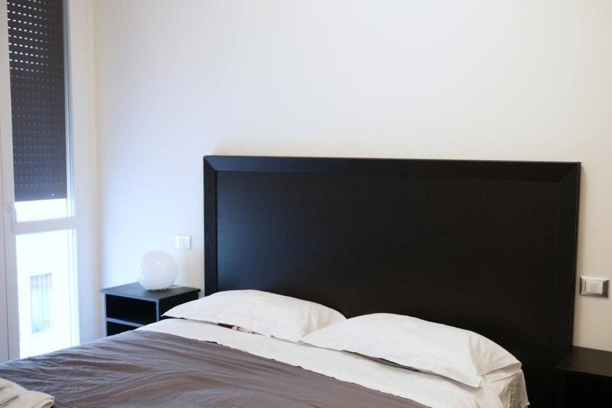 Ein Schlafzimmer mit einem großen Bett, einem Nachttisch und einer Wandlampe.