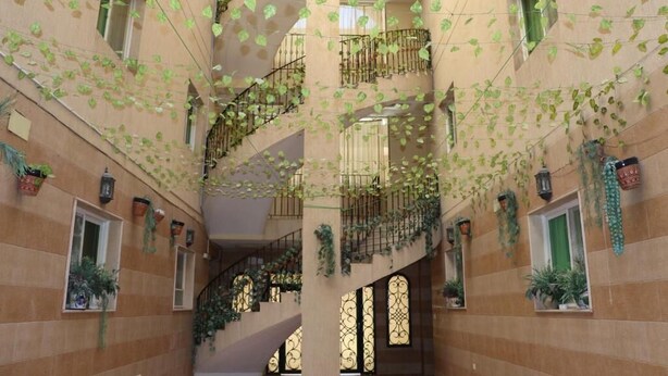 A multi-level atrium with balconies, staircases, and potted plants.