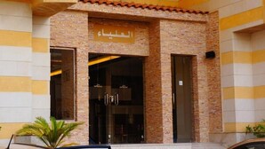 A hotel entrance with a stone facade and a sign in Arabic.