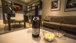 Una mesa de comedor con una botella de vino, dos copas y fuentes de aperitivos.