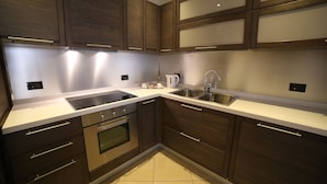 Una cocina moderna con armarios de madera oscura, electrodomésticos de acero inoxidable y encimera blanca.