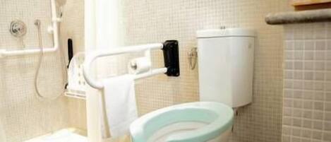 A bathroom with a toilet, grab bars, and a shower.