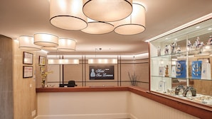 A hotel reception area with a wooden reception desk, multiple pendant lights, framed certificates, and a glass display case with souvenirs. - Hotel San Lorenzo (Santiago de Compostela)