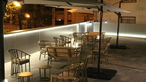 An outdoor seating area with tables and chairs, a bar counter, and umbrellas providing shade. - Hotel San Lorenzo (Santiago de Compostela)