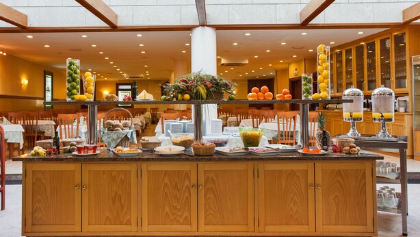 A buffet setup with various food items and beverages, wooden cabinets, and a central column. - Hotel San Lorenzo (Santiago de Compostela)