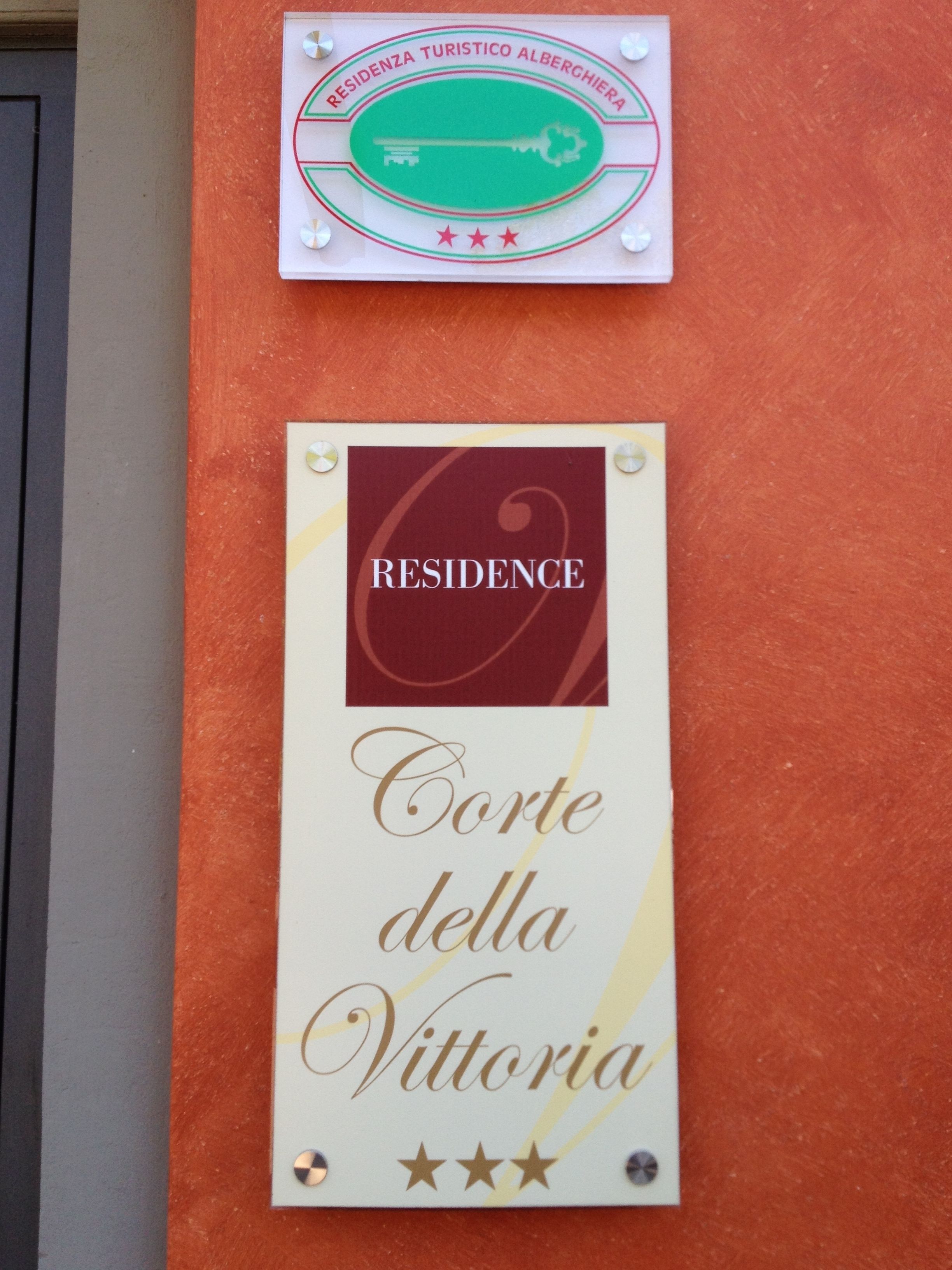 Un segnale con la scritta 'RESIDENCE Corte della Vittoria' e un simbolo di chiave, che indica un'opzione di alloggio.